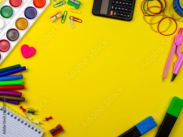 Fototapeta School conception, multicolored paints, pencils, markers and paper clips. School calculator and other items for the student and school on a yellow background. Flatlay, top view, copy space.