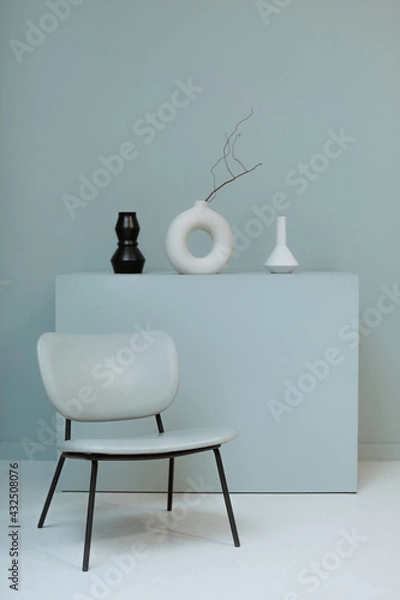 Obraz A blue chair against the background of a minimalistic composition and a plain wall. Stylish interior design