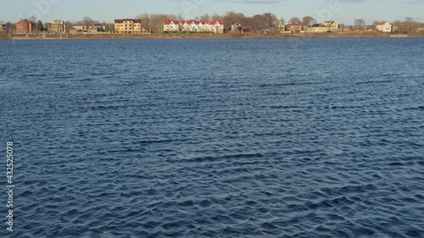 Obraz The water surface of the river with a slight excitement, buildings on the bank