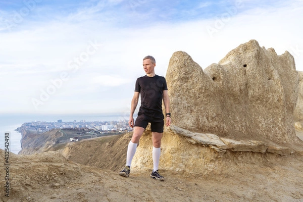 Fototapeta Man standing on mountains, looking on horizon