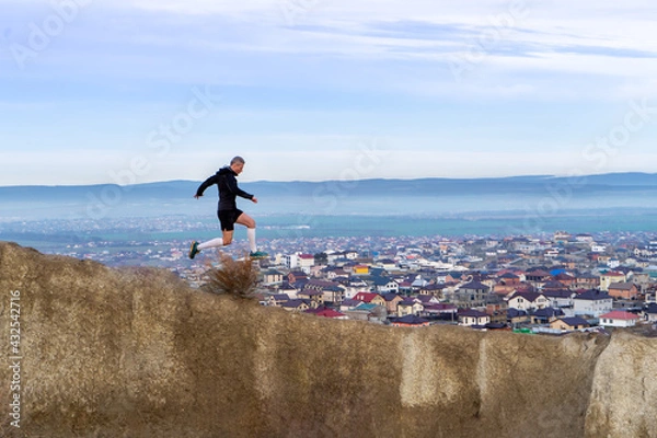 Fototapeta Man running in mountains and houses background