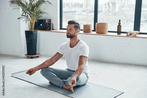 Fototapeta Totally relaxed young man doing yoga while sitting 