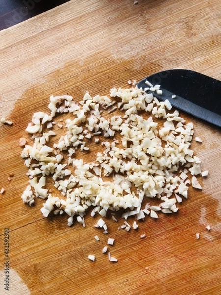 Fototapeta Sliced garlic cloves on wooden chopping Board