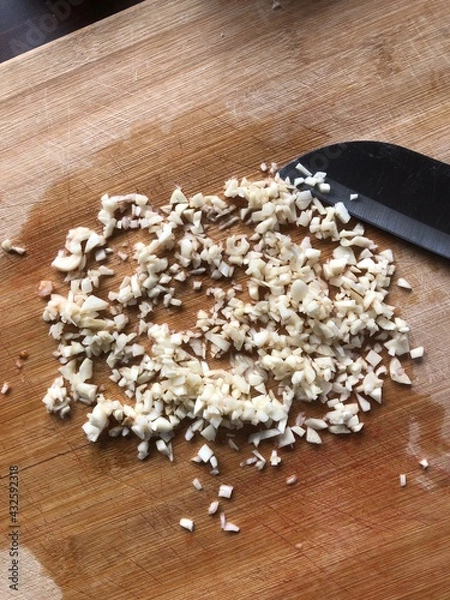 Fototapeta Sliced garlic cloves on wooden chopping Board