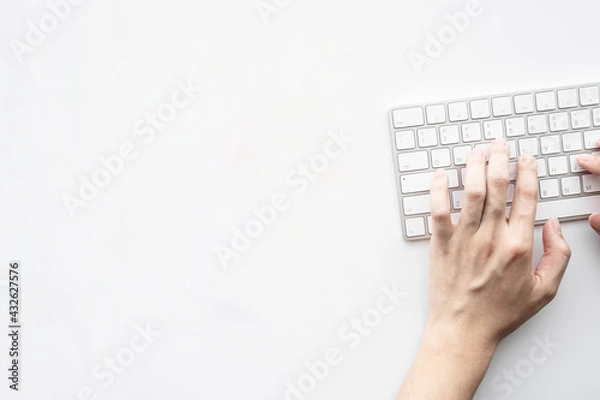 Fototapeta Man is typing on laptop keyboard over white office desk table. Top view with copy space, flat lay.
