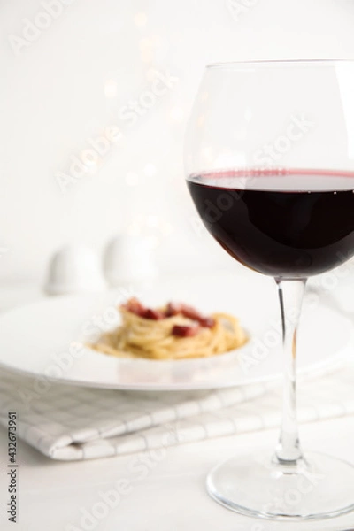 Fototapeta Delicious Carbonara pasta, focus on glass of wine. Space for text