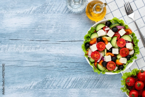 Fototapeta Greek salad or horiatiki salad made with pieces of tomatoes, cucumbers, onion, feta cheese, bell pepper slices, olives and dressed with olive oil. Healthy food concept, vegetarian breakfast or lunch.