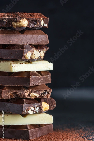 Fototapeta Stack of milk and dark chocolate with nuts, caramel and fruits and berries on dark marble background..