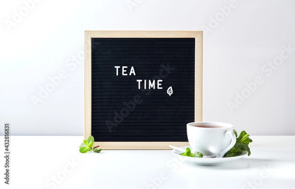 Fototapeta Tea time. Black letter board with text on table with glass cup of tea with mint leaves
