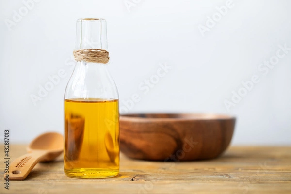 Fototapeta Olive oil in a bottle, a spoon, a plate on a wooden table on a white background. Copy space.