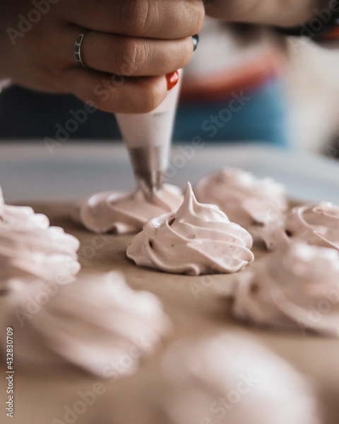 Fototapeta Girl squeezes out cream roses, meringues, marshmallows on a baking sheet from a pastry bag. Desserts, cooking cover