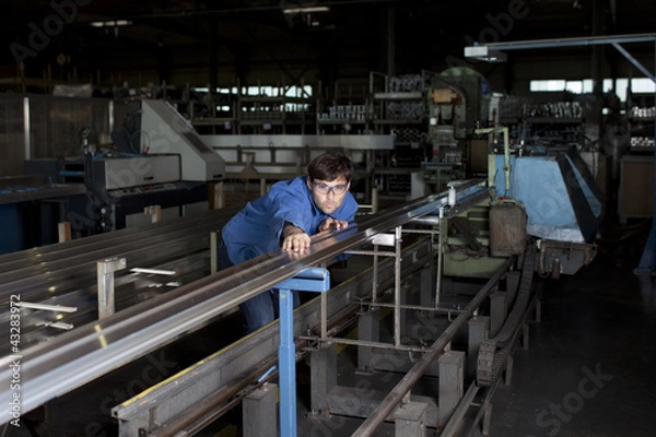Fototapeta Blue collar worker at machine in factory