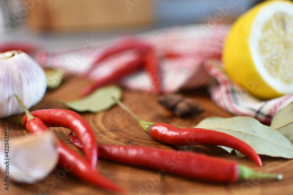 Obraz Hot chili peppers, lemon, garlic and spices on a wooden board