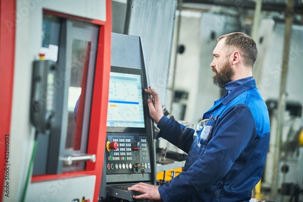 Fototapeta Industrial worker operating cnc machine at metal machining industry