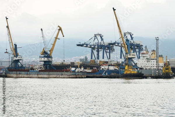 Fototapeta Loading and unloading operations in the water area of the sea cargo port in bad weather. Copy space.