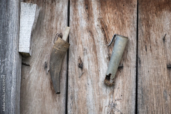 Fototapeta Old, rustic sharpener rock for lawn mower against a wooden, red wall of a shed in a Serbian village