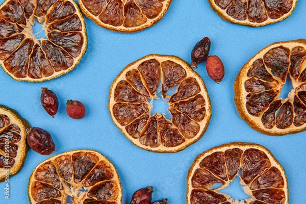 Fototapeta dried oranges and rose hips on a blue background