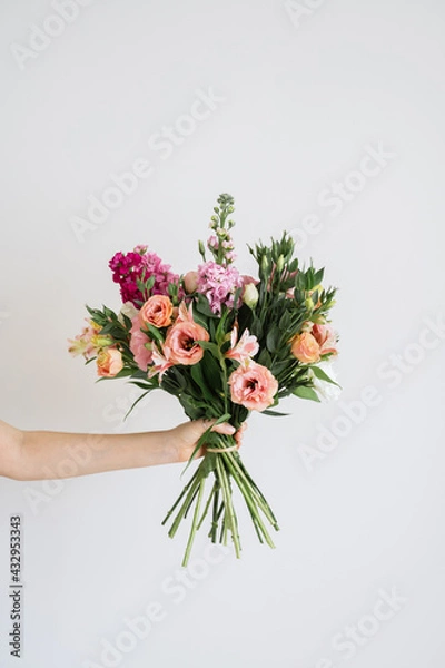 Fototapeta Cropped shot of female holding big beautiful gorgeous spring wedding bouquet of different fresh flowers in full bloom against white background with copy space for text. Floristry work concept