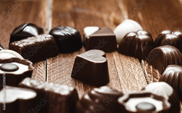 Fototapeta Close-up of a heart-shaped chocolate bonbon surrounded by several bonbons. International Chocolate Day. Copy Space