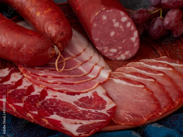 Fototapeta Food tray with delicious salami, prosciutto crudo or jamon, fresh sausages and herbs. Meat platter with selection.
