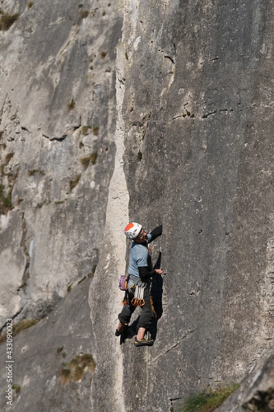 Obraz Male climber with a helmet explores the climbing route.