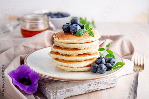 Fototapeta Homemade pancakes with blueberries and powdered sugar on the white table