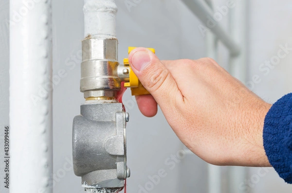 Obraz Male hand opens or closes natural gas valve in home boiler room