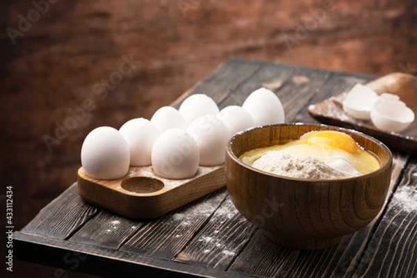 Fototapeta flour and eggs on a wooden table in country style