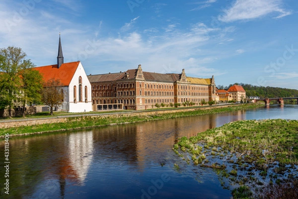 Fototapeta Grimma, Saxony, Germany- 05 11 2021, the small town on the river Mulde -Modern flood protection wall in the style of the historic city wall, Augustin High School