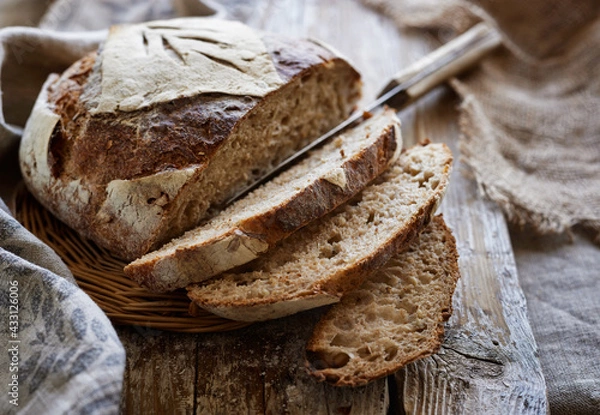 Fototapeta Traditional sourdough bread, sliced on a wooden board, close-up view