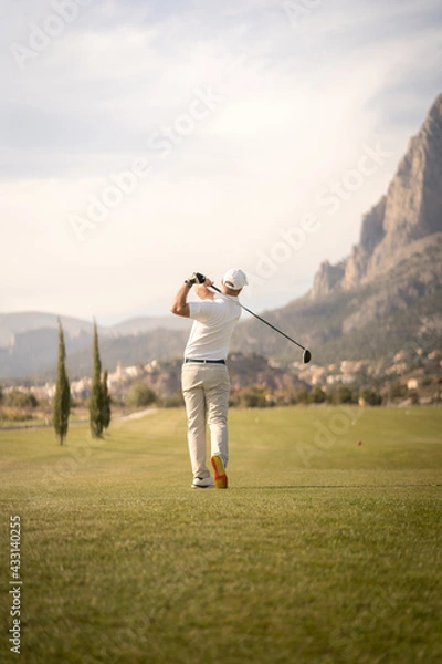 Fototapeta Golf player making a perfect swing on the golf course in the sunset.