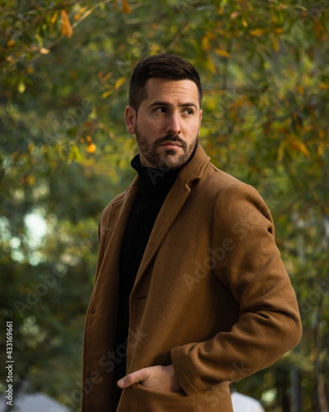Fototapeta Fall portrait of a bearded man with a brown coat at sunset time in the park