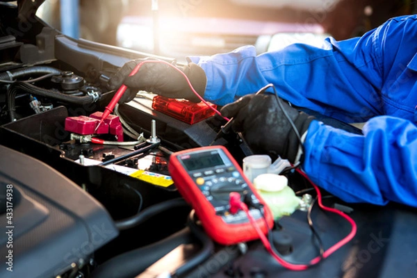 Fototapeta Technician uses multimeter voltmeter to check voltage level in car battery. Service and Maintenance car battery.