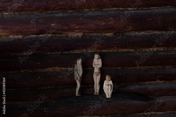 Fototapeta three human figures on the background of a log wall