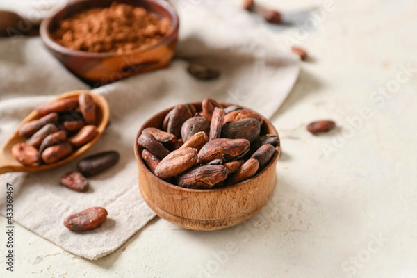 Fototapeta Bowl with cocoa beans on light background