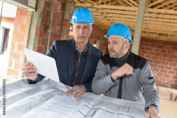 Obraz Architect and contractor checking the plans on a construction site