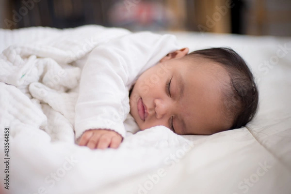 Fototapeta Infants are looking forward in an upside-down position on a white bed, the evolution of Baby girl in the age up to 6 months./Selected focus