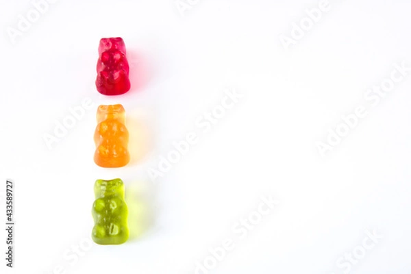 Obraz Three gummy bears in colours of traffic lights lined up vertically, isolated on white background with copy space