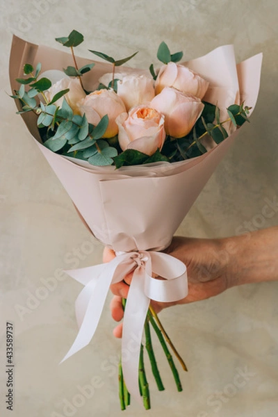 Fototapeta Bouquet of delicate peony roses of peach color with eucalyptus in a paper package. Summer background.