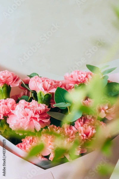 Fototapeta Delicate bouquet of coral carnations with eucalyptus greens with green bokeh. Summer background