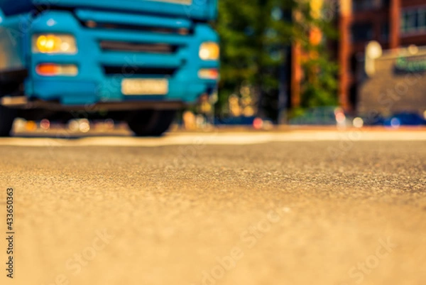 Fototapeta Summer in the city, the truck traveling on the avenue. Close up view from the asphalt level