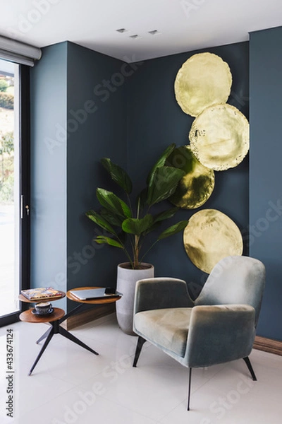 Obraz Vertical shot of a modern house with a big plant next to small round tables and comfortable chair