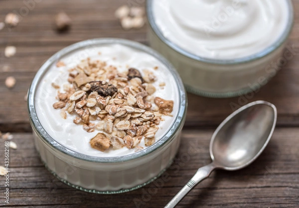 Obraz White yogurt in glass bowl with oatmeal on top on rustic wooden desk.