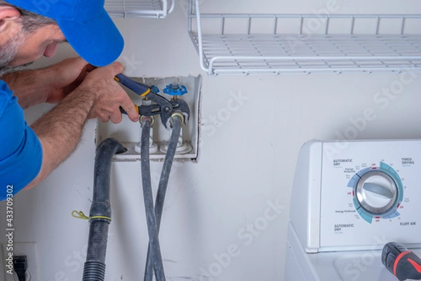 Fototapeta Plumber hooking up supply lines for a washing machine