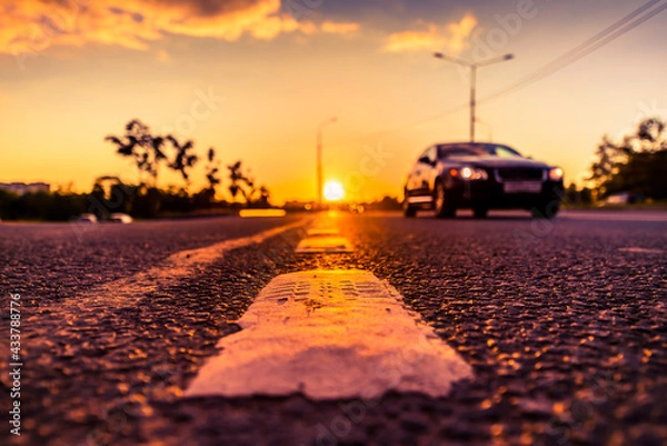 Fototapeta Sunset in the country, the car on the highway. Wide angle view of the level of the dividing line
