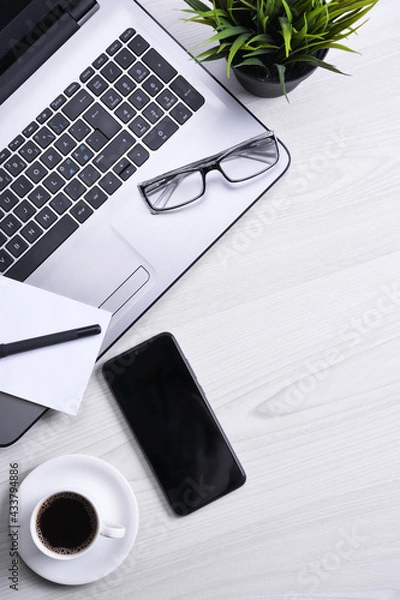 Fototapeta Top view of office work space, wooden desk table with laptop notebook,keyboard ,pen,eyeglasses,phone,notebook and cup of coffee.With copy space, flat lay.Mock up.