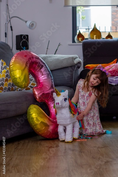 Obraz A Cute Baby Girl Sitting On The Floor With a Balloon And An Unicorn Pinata