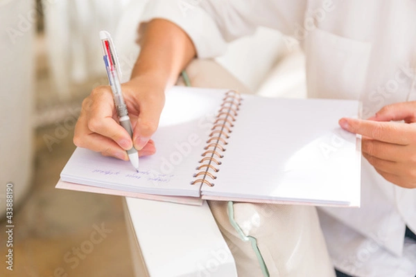 Fototapeta Businesswoman makes a note in notebook. Pen in hand