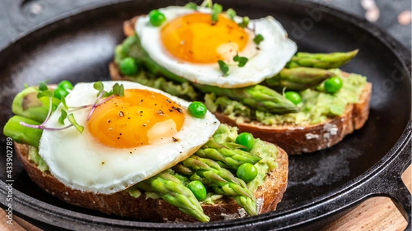 Obraz Tasty breakfast toasts with avocado, asparagus and fried egg. Healthy food, diet lunch concept, top view