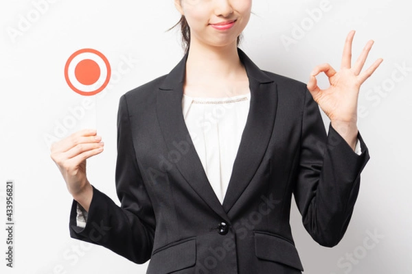 Fototapeta 白バックの前に立って、OKのプラカードを持つビジネスウーマン